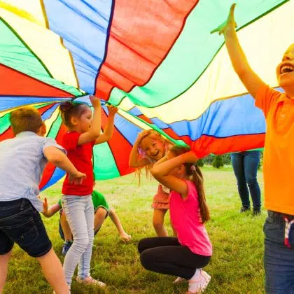 Close up view of children playing hide-and-seek under the huge rainbow cover